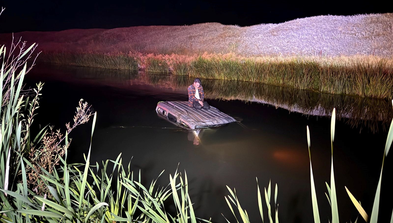 Nehre düşen aracının üstünde yardım bekledi